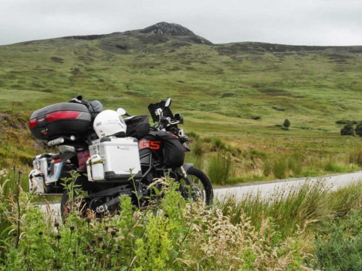 Una moto da viaggio lungo una strada nel paesaggio scozzese
